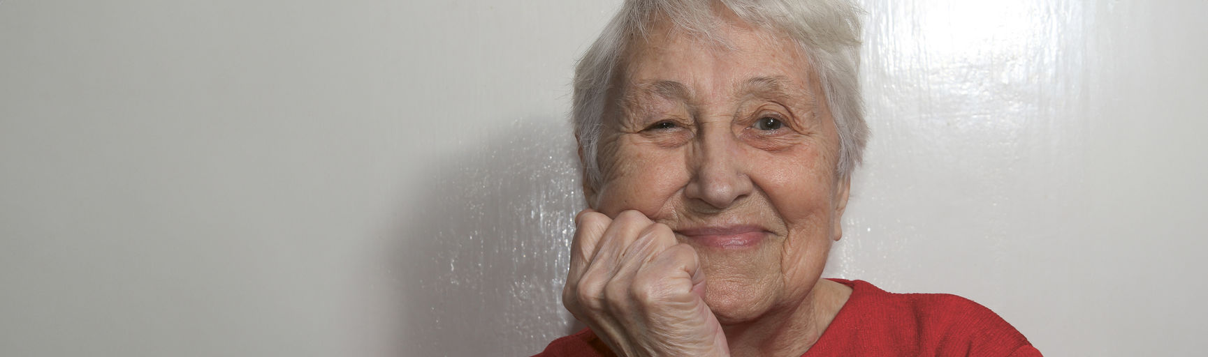 Ältere Dame sieht in die Kamera und lächelt